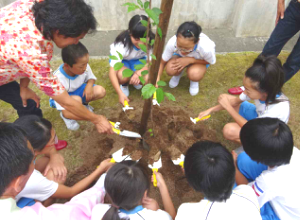 こどもと一緒に植樹した木に水をかける様子