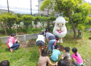 メリーちゃんと子ども達が植樹をしている写真
